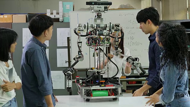 年轻的电子工程师团队在车间协作建造机器人。团队工程师一起启动机器人项目。有技术或创新观念的人。视频素材