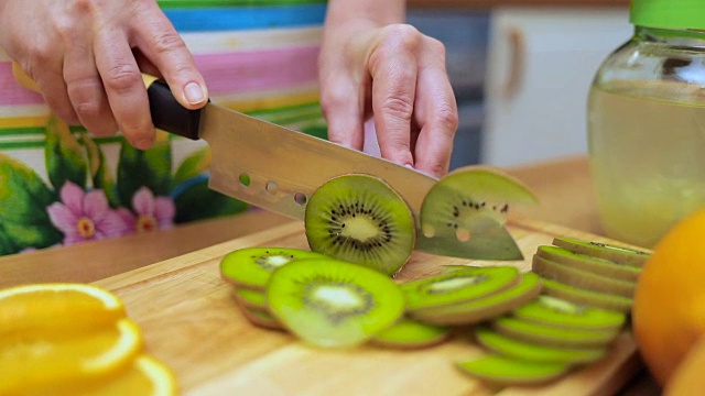 主妇们用刀在厨房餐桌的砧板上切着新鲜的猕猴桃视频素材