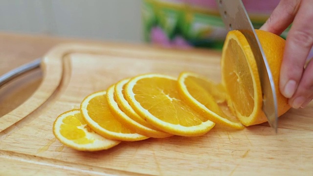 妇女的手家庭主妇用刀在厨房餐桌的砧板上切新鲜的橘子视频素材
