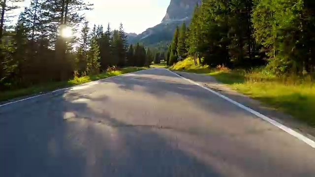 在夕阳西下的森林中行驶在蜿蜒的道路上视频下载