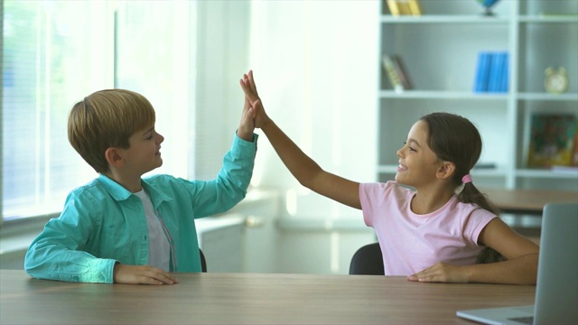 快乐的男孩和女孩在桌子旁打招呼。慢动作视频下载