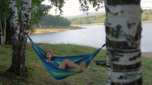 快乐的女孩躺在大自然的吊床上视频下载