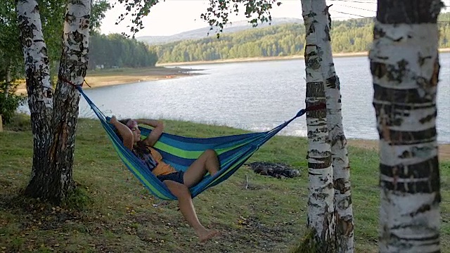 嬉皮女孩躺在大自然的吊床上视频下载