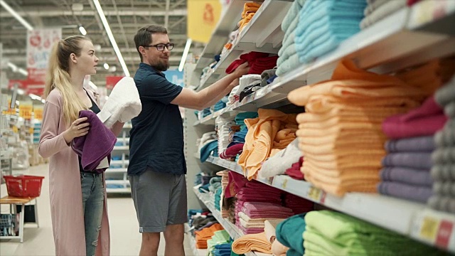 配偶们在商店里检查各种各样的毛巾，决定买什么颜色的视频素材