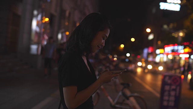 年轻的亚洲女孩看着手机走路，4k视频素材