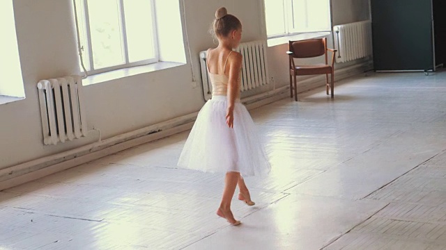 年轻的女孩穿着白色芭蕾舞裙表演小的芭蕾舞跳跃视频素材