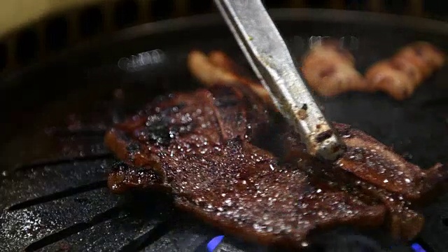 韩国烧烤架。人们在餐馆里用韩式烧烤做菜吃。4 k,特写。视频下载