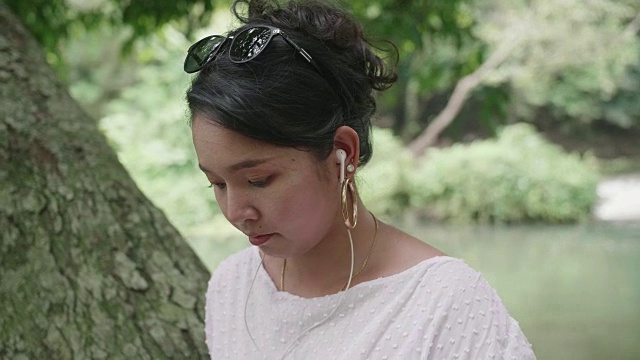 年轻的亚洲女人用耳机听音乐。视频素材