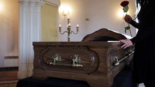 悲伤的女人在葬礼上将红玫瑰放进棺材视频下载