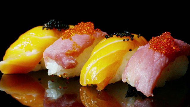 寿司，生鱼片，浦城和夜拍的微距镜头。典型的日本菜，包括米饭、鲑鱼或金枪鱼、虾和浸在酱油中的鱼卵。视频素材