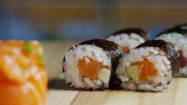 寿司，生鱼片，浦城和夜拍的微距镜头。典型的日本菜，包括米饭、鲑鱼或金枪鱼、虾和浸在酱油中的鱼卵。视频素材