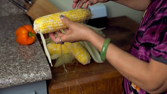 年老的亚洲妇女清洁和准备玉米在她的厨房做饭视频下载