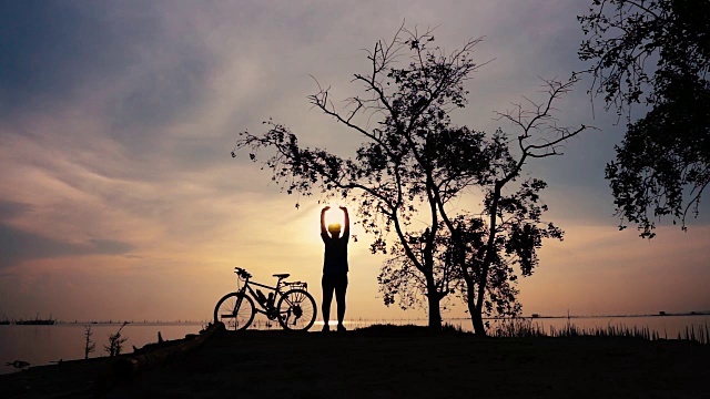 骑自行车的妇女在海边散步的剪影，伸展运动。视频下载