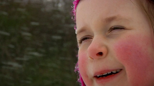 慢镜头:小女孩在雪地里眨着眼睛视频素材