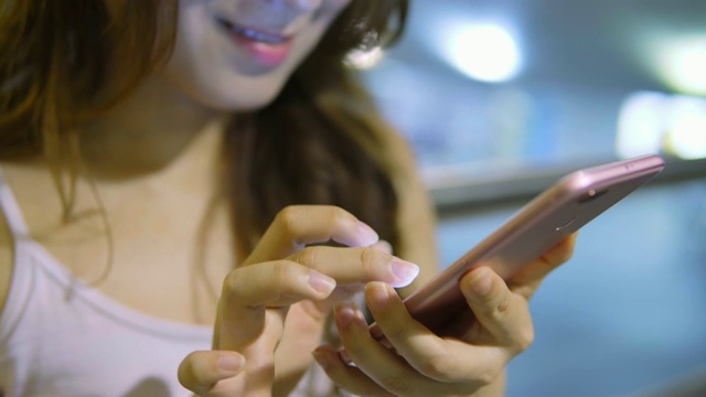 年轻的亚洲女性在晚上使用智能手机视频素材