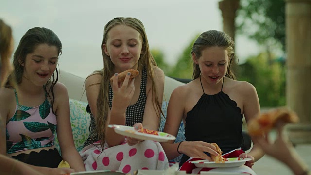 快乐的女孩坐在池边笑着吃比萨饼/雪松山，美国犹他州视频素材