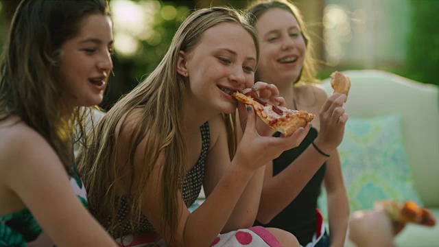 快乐的女孩坐在泳池边笑着吃披萨的特写/雪松山，犹他州，美国视频素材