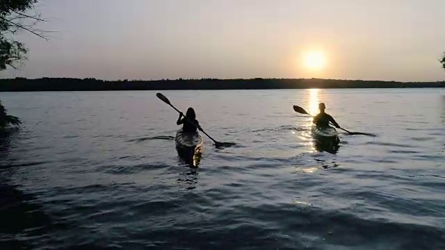 两个皮划艇和人们在河上欣赏美丽的日落视频素材