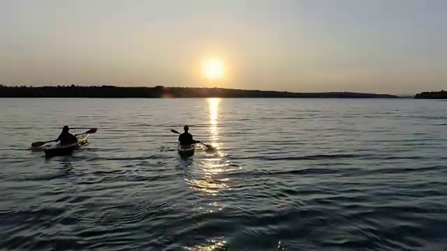两个皮划艇和人们在河上欣赏美丽的日落视频素材