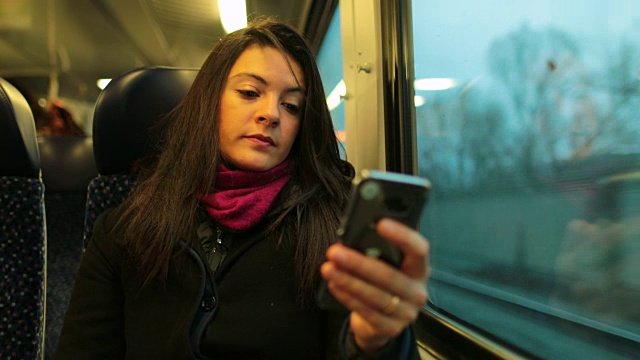 坐火车时拿着手机的女人。女孩手持4K智能手机的特写视频素材