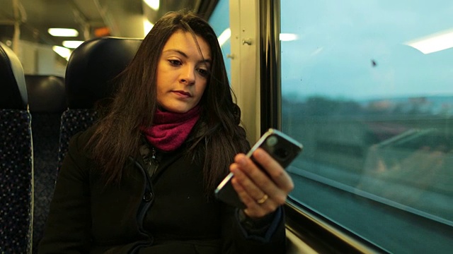 坐火车时拿着手机的女人。女孩手持4K智能手机的特写视频素材