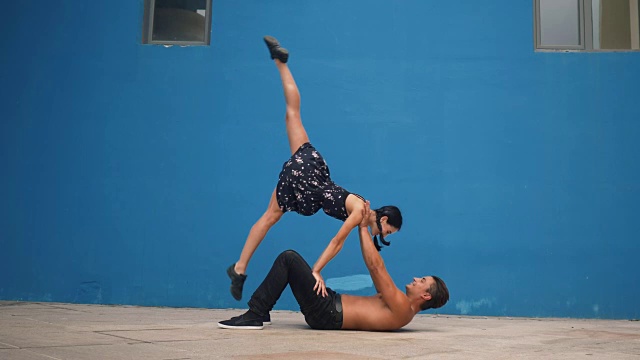 舞者在蓝色背景下用慢动作表演杂技，展示感官舞蹈模式。在城市的户外跳舞视频素材