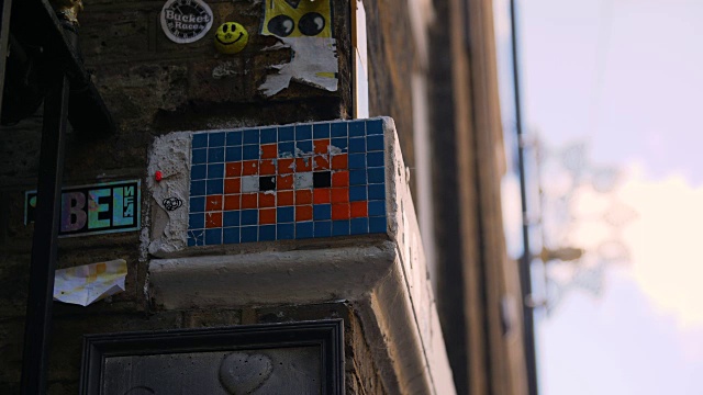 一幅由街头艺术家“入侵者”创作的马赛克瓷砖作品被贴纸和其他艺术品包围着视频下载