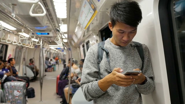 在地铁里拿着智能手机的亚洲男人视频下载