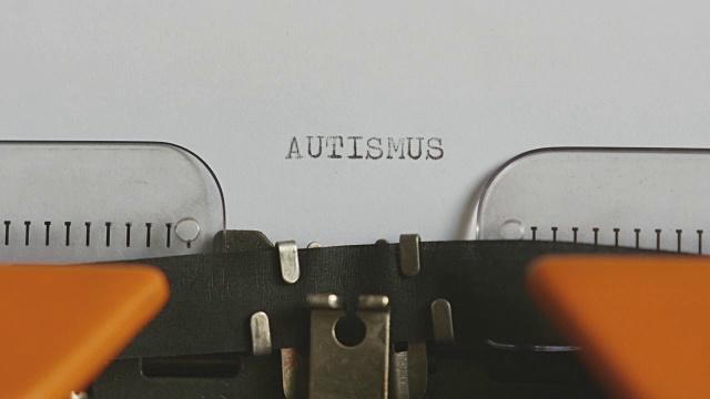 一个人用德语写“自闭症”的特写镜头，在一台老式打字机上，带有声音视频素材