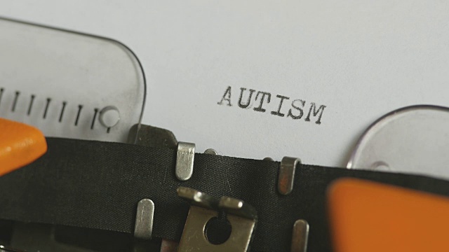 一个人用声音在一台旧打字机上写自闭症的特写镜头视频素材