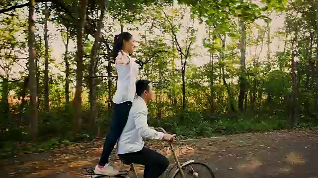 年轻幸福的夫妇喜欢在自然的道路上骑自行车，爱和关系的概念视频下载