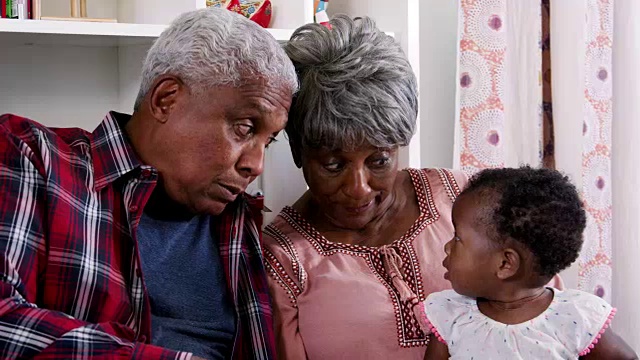 爷爷奶奶和小孙女坐在家里一起看书视频素材