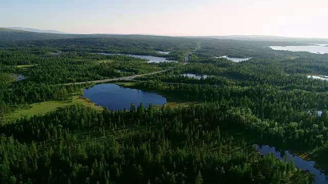 鸟瞰图蓝色的湖泊和绿色的森林在一个阳光明媚的夏天在芬兰。视频下载
