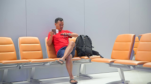 亚洲旅行者在等待飞机航班时使用手机视频下载