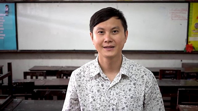 年轻英俊的亚洲男老师在教室里微笑的肖像视频下载