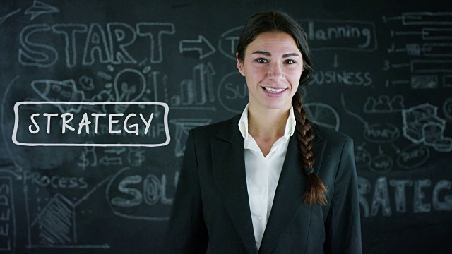 未来主义的肖像，一个美丽的商业女孩(学生)作出选择的成功在一个黑板的背景。视频素材