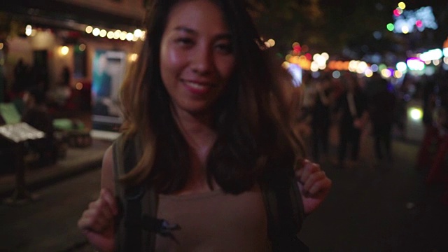 慢镜头——在泰国曼谷的考山路，年轻的亚洲旅行女性背包客在城市的街头派对上喝着酒或啤酒跳舞。旅行者和游客的概念。视频素材