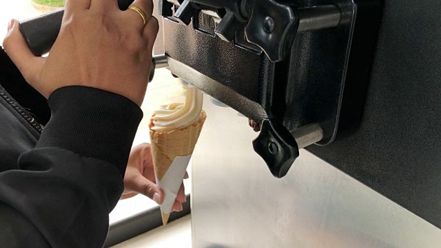 女填充物旋转一个蛋筒与软冰淇淋从机器视频素材