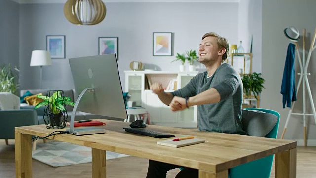 英俊的年轻人坐在电脑前跳舞的肖像。年轻人在家里玩。视频素材