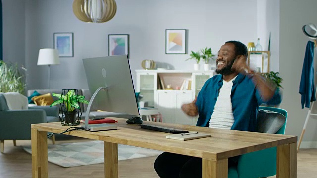 英俊的非裔美国人坐在他的工作场所跳舞的肖像。年轻人在家里玩。视频素材