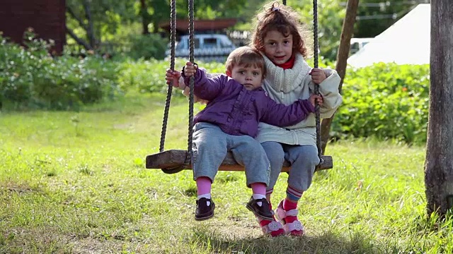 两个小女孩在后院的绳上荡秋千视频素材