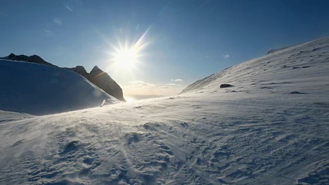 暴风雪吹在有阳光的雪山上视频素材