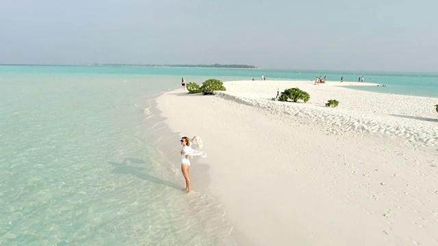 无忧无虑的女人伸开双臂走在阳光明媚的马尔代夫田园般的热带海滩上视频素材