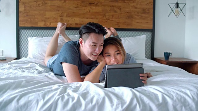 夫妇在床上使用电子平板电脑视频素材