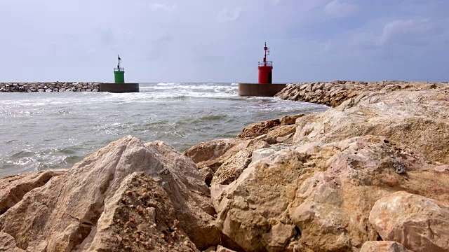 海流击中港口入口的绿色和红色灯塔塔。视频素材