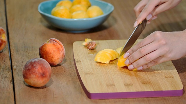 用刀在木板上切多汁的桃子。视频购买