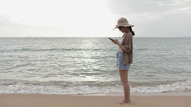 在海滩使用手机的亚洲女性视频素材