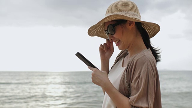 在海滩使用手机的亚洲女性视频素材