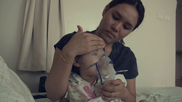小女孩和她妈妈在医院用吸入器口罩呼吸。视频素材