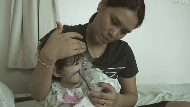 小女孩和她妈妈在医院用吸入器口罩呼吸。视频素材